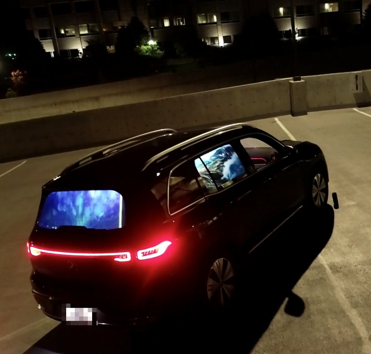 A black SUV parked at night with its back windshield and rear side window lit by HoloGlass