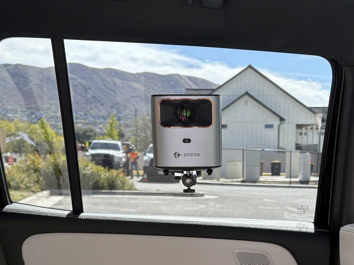 The HoloGlass unit mounted upright on a rear side window inside a car, with the included suction-cup mount