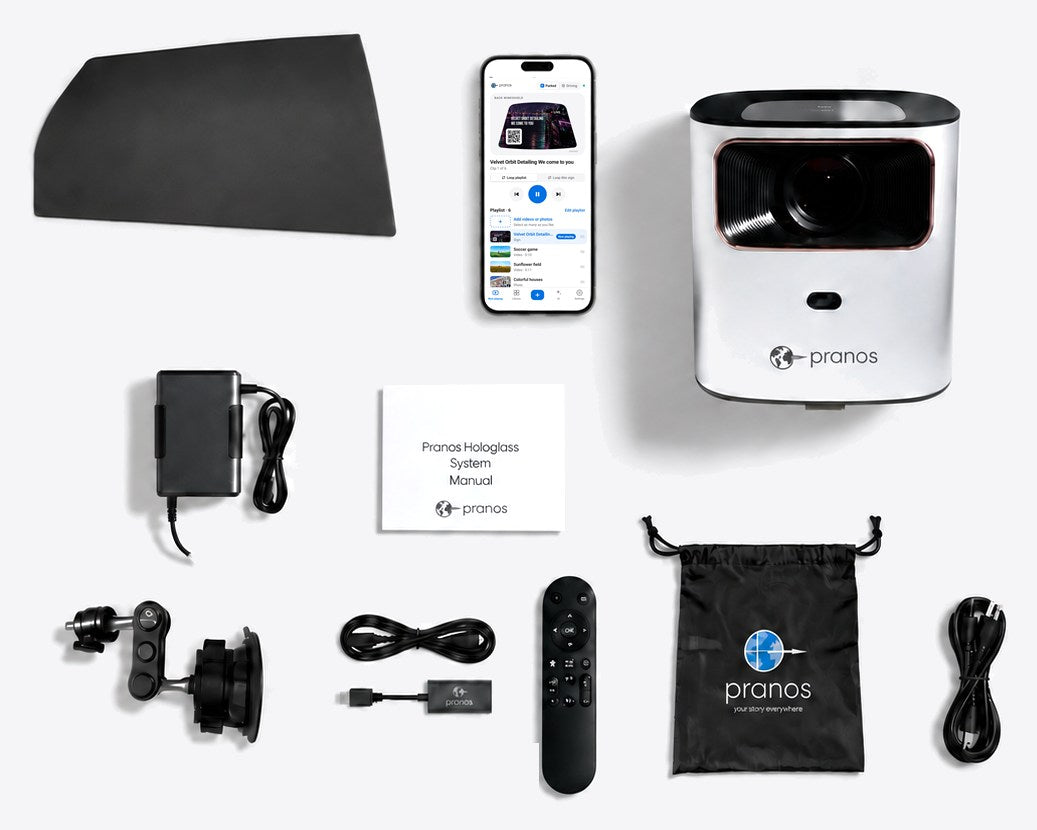 Everything in the kit, laid out: the screen made for your car’s window, the Pranos app on a phone, the HoloGlass unit, the power inverter, the setup guide, the suction-cup mount, the HDMI cable and USB-C phone adapter, the remote, the storage bag and the power cable